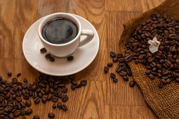 Coffee cup on dark wood with roasted coffee beans, espresso and white flower, Kaffee Tasse 