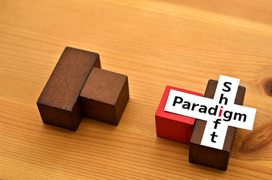 There is a piece of paper with the word "Paradigm Shift" on colored blocks.
