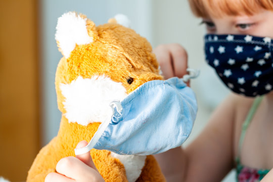 Young girl training to use a face mask during the pandemic -Focus on the teddy