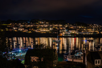 town lit up at night with reflection on water with boats
