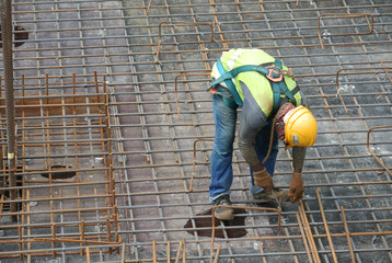MALACCA, MALAYSIA -MAY 27, 2016: Construction workers fabricating steel reinforcement bar at the construction site in Malacca, Malaysia. The reinforcement bar was ties together using tiny wire.  
