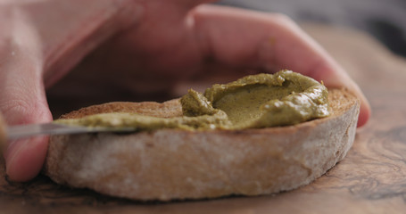 man spread pistachio cream over ciabatta slice closeup