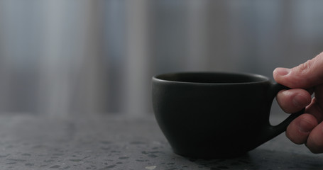 Obraz na płótnie Canvas man hand put empty black cup on terrazzo countertop