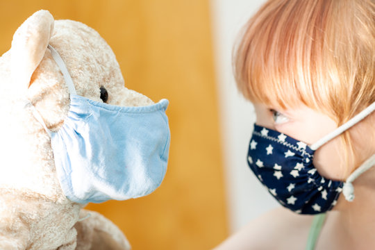 Young girl training to use a face mask during the pandemic -Focus on the teddy