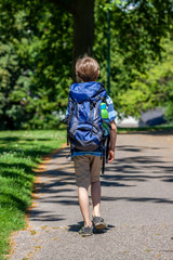 Fototapeta premium Boy hiking in the park with huge rucksack