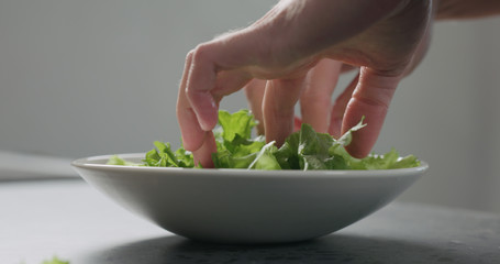 man add frisee salad leaves into white bowl