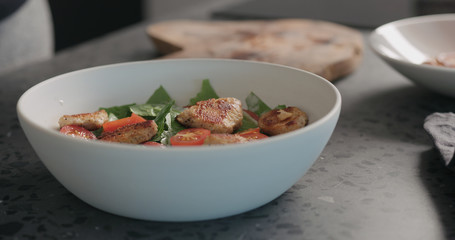 making caesar salad in white bowl , put chicken pieces