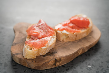 Sandwich with smoked salmon and cream cheese on olive woob board