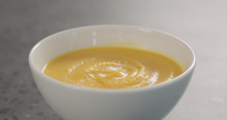 Pumpkin cream soup in white bowl on concrete background