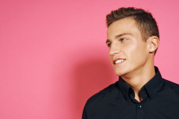Obraz premium Man in black shirt gestures with hands lifestyle pink isolated background