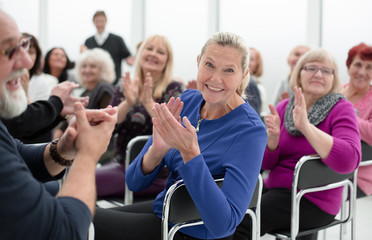 a group of elderly people are sitting in a circle clapping their