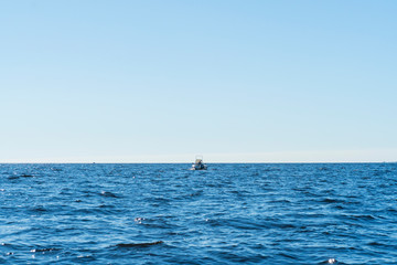 Fisherman on boat in blue ocean. Beautiful seascape with the fishing boat. Fishing motor boat with angler. Ocean sea water wave reflections. Motor boat in the ocean.