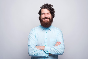 Portrait of happy smiling bearded man in blue shirt with crossed arms looking at the camera.