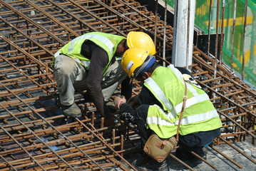 MALACCA, MALAYSIA -MAY 27, 2016: Construction workers fabricating steel reinforcement bar at the construction site in Malacca, Malaysia. The reinforcement bar was tied together using tiny wire.  