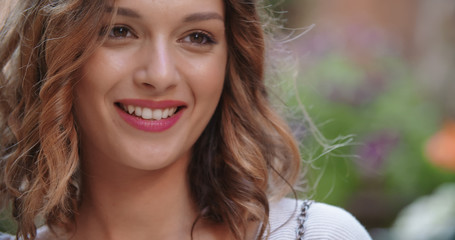 Fototapeta premium handheld portrait of woman smiling outdoor in urban environment.Young happy woman portrait. Front view, close-up.Woman looking something and smiling