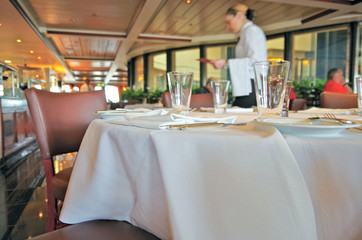 Formal dining room or steak house restaurant with set tables on modern Norwegian cruise ship or...