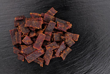 Beef jerky meat slices on a slate stone background
