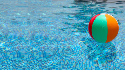 Beach ball in pool. Colorful inflatable ball floating in swimming pool, summer vacation concept.