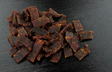 Beef jerky meat slices on a slate stone background