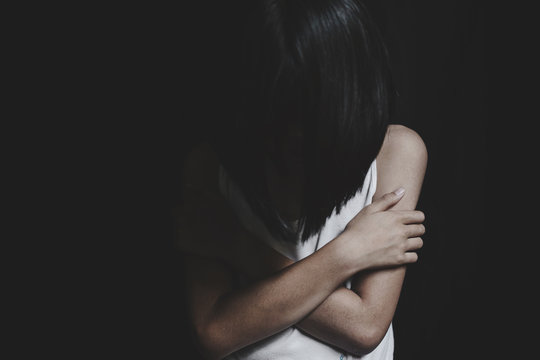 Portrait of sad little girl standing on black background, fear child,