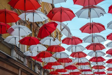 Fototapeta na wymiar Umbrellas in the sky above city streets