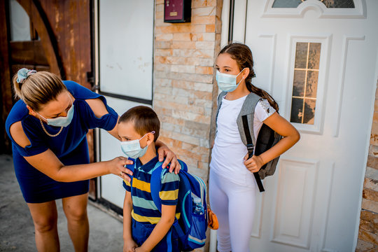 Boy And Girl Going Back To School. They Are Wearing A Protective Face Mas