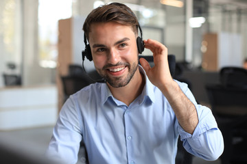 Smiling friendly handsome young male call centre operator. - obrazy, fototapety, plakaty