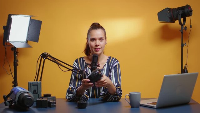 Social media star reviewing two camera lenses in her professional studio. Content creator new media influencer talking video photo equipment for online internet web show