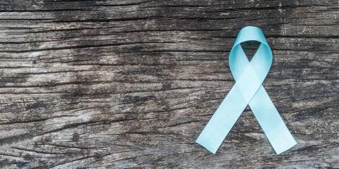 Blue awareness ribbon for prostate cancer, men health and diabetes in November with pale light blue bow color on medical doctor record, male patient healthcare concept