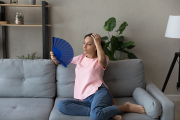 Tired indian Arabic young woman sit relax on couch in living room breathe fresh air form waver...