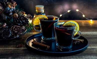 Christmas mulled wine with oranges and spices on wooden background.