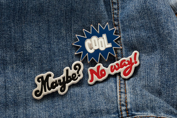 Close up view of denim jacket with graphic pin, funky metallic fashion accessory