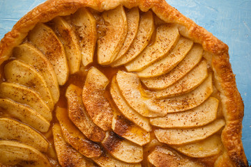 Homemade organic pie with apples puff pastry, cinnamon and butter. Delicious apple puff with blue background.