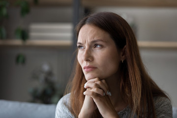 Unhappy young red-haired Caucasian woman look in distance thinking of life problems troubles, upset millennial female pondering at home, feel worried anxious, struggle with difficulties