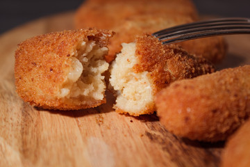 Homemade traditional spanish croquettes on a wood board and black background. Tapas food. Dark food.