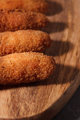 Homemade traditional spanish croquettes on a wood board and black background. Tapas food. Dark food.