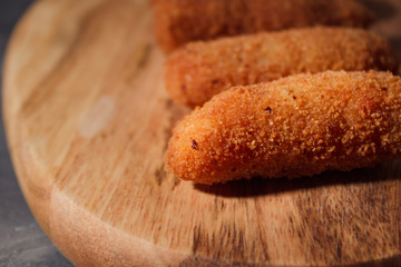 Homemade traditional spanish croquettes on a wood board and black background. Tapas food. Dark food.