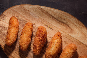 Homemade traditional spanish croquettes on a wood board and black background. Tapas food. Dark food.