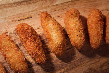 Homemade traditional spanish croquettes on a wood board and black background. Tapas food. Dark food.