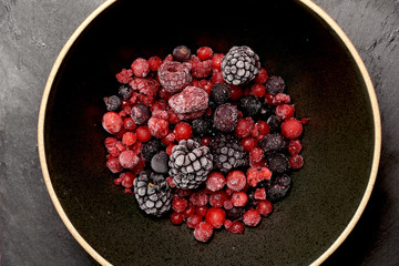 Red berries and black berries on a black plate and slate background. flat lay. organic gastronomic food