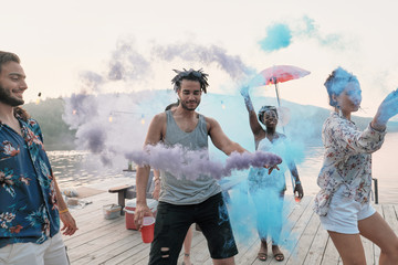 Group of friends standing on a pier and dancing they visiting festival of colors