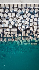 Obraz premium Aerial view of a young man on a cement cube blocks protecting the shore from the waves in the port of Malaga, Spain.