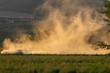 Farm tractor tilling the land and kicking up a lot of dust