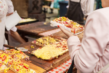 woman takes piece of pizza in street market
