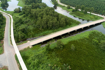 Aerial view drone shot of road between green field summer forest and river and lake in suratthani Thailand.