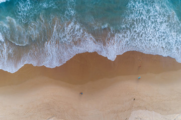 Fototapeta na wymiar Aerial view sandy beach and crashing waves on sandy shore Beautiful tropical sea in the morning summer season image by Aerial view drone shot, high angle view Top down.