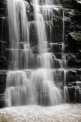 Fototapeta na wymiar Close up of a small waterfall in the Ribble valley. Falling water into a deep pool.