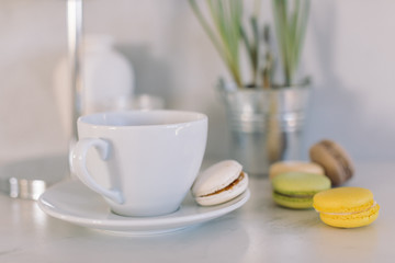 Morning cup of coffee, macaroons and muscari in pot. Spring concept. Still life in modern interior.
