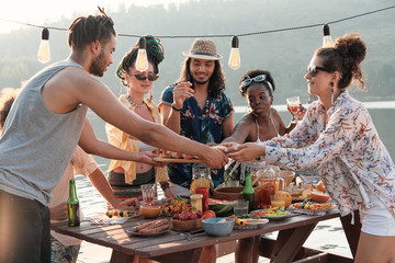 Group of friends eating hot dogs during the lunch on fresh air