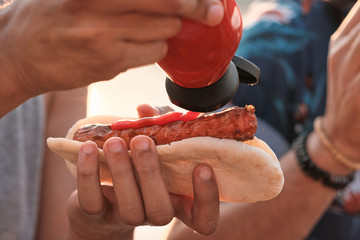 Close-up of man eating hot dogs with ketchup at picnic outdoors